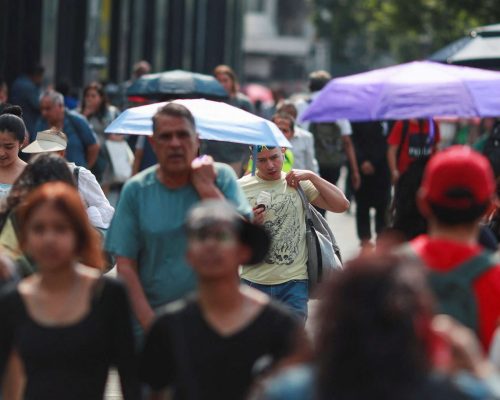 People cover themselves with umbrellas next to others as they walk along a sidewalk during high temperatures, in Mexico City, Mexico May 9, 2024. REUTERS/Henry Romero